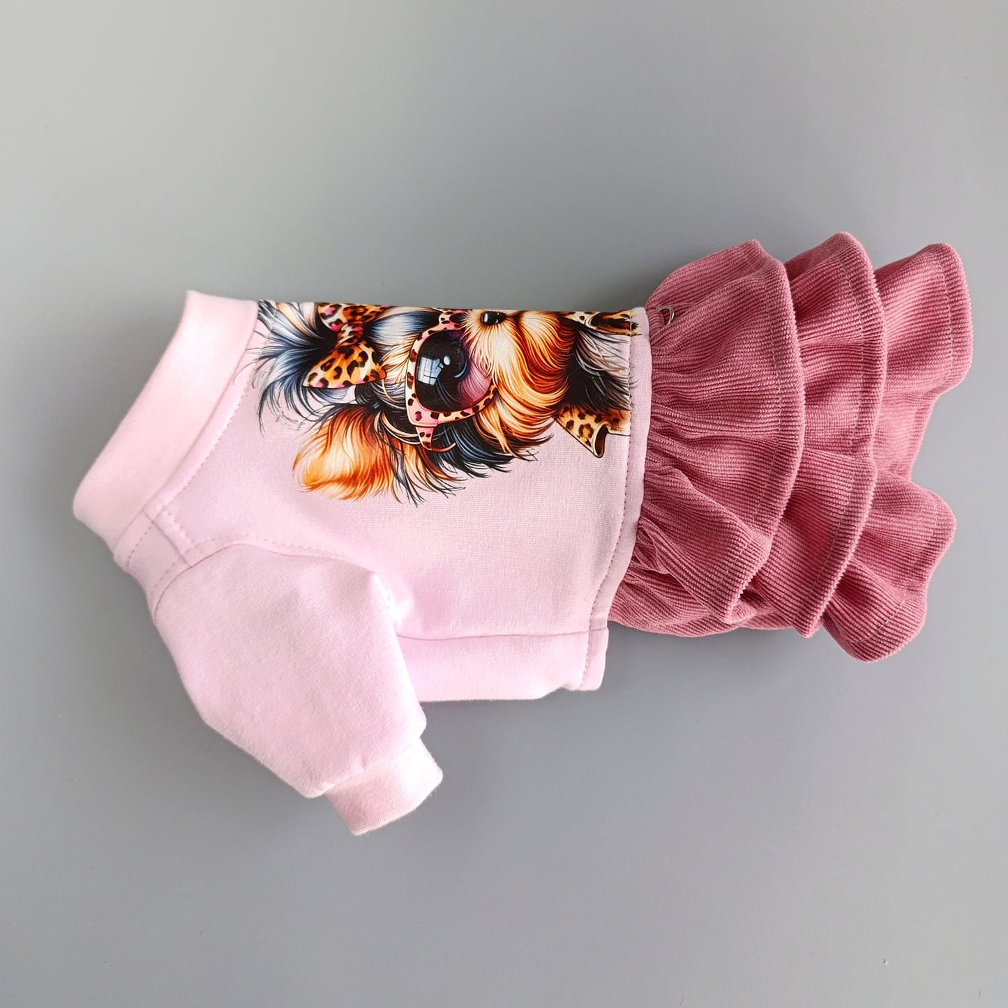 Pink pet outfit with ruffled details and a colorful feather design